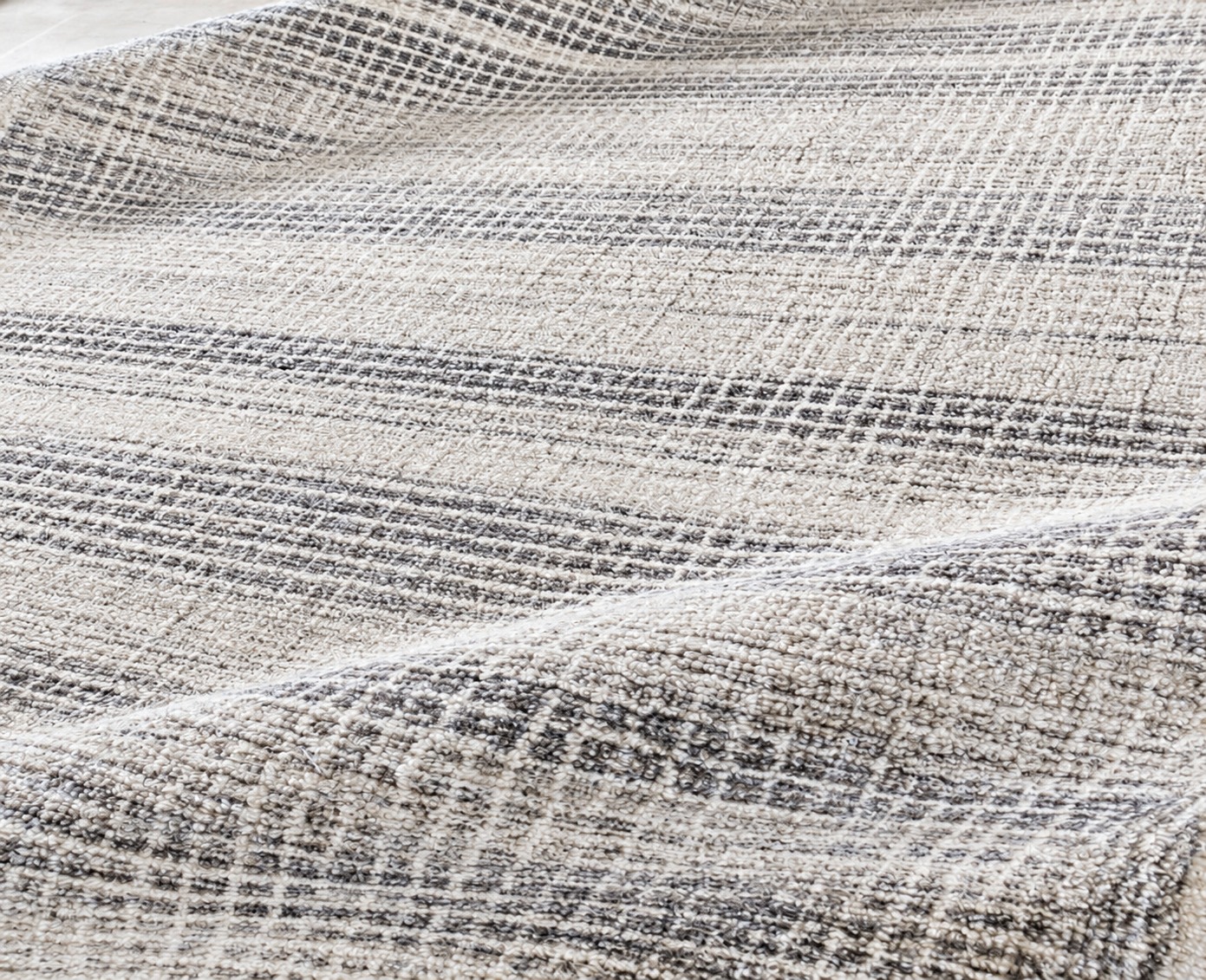 Close-up of folded ivory and grey textured rugs